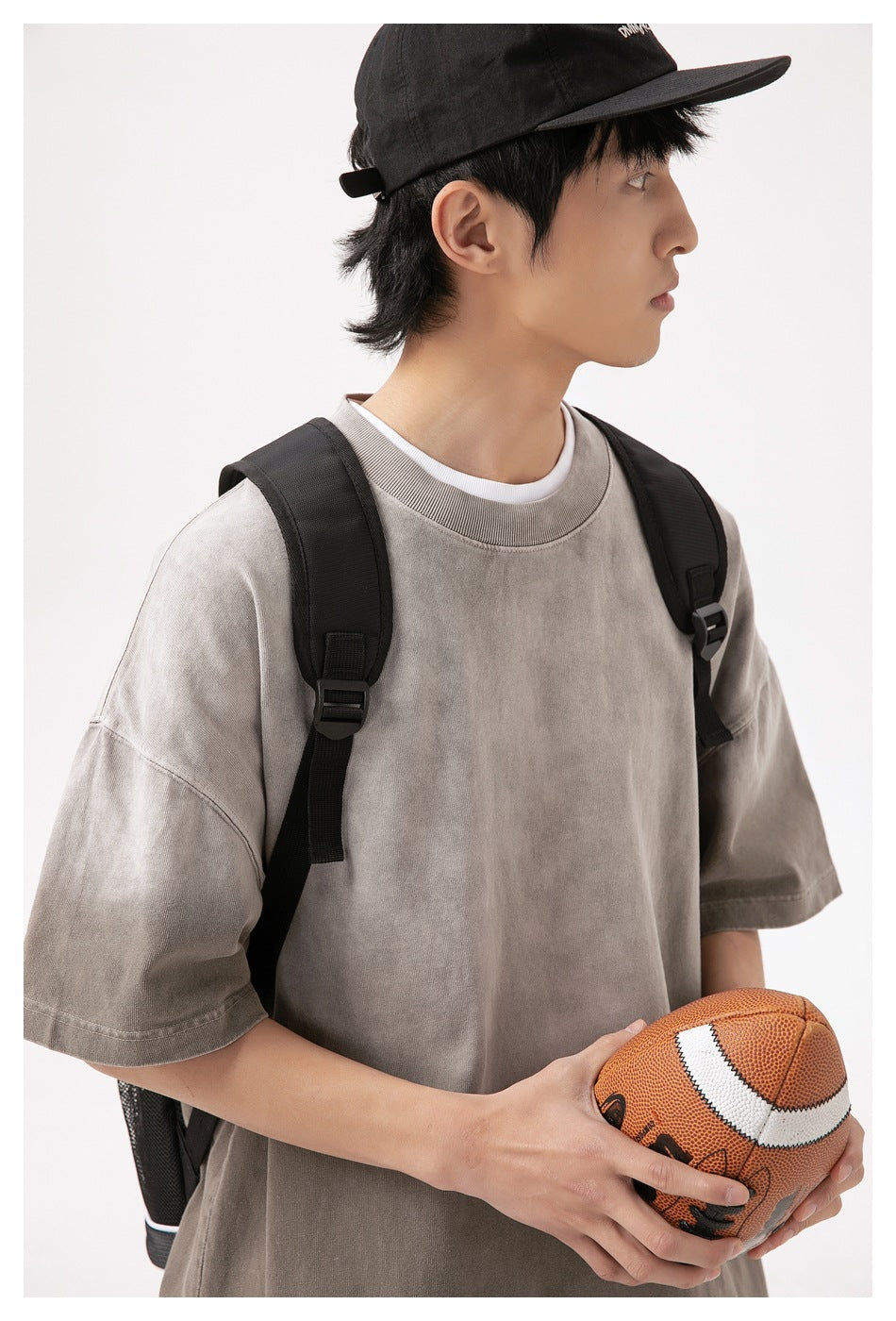 Close view of a model wearing an oversized taupe-gray T-shirt with a ribbed crew neck.
