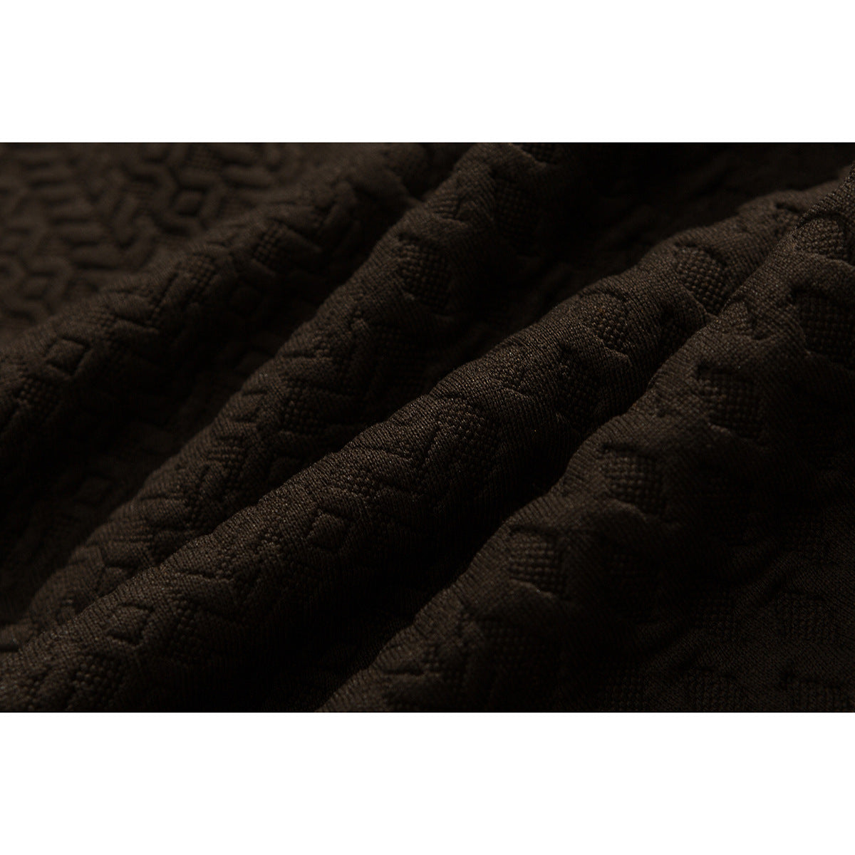 Extreme close-up of dark brown fabric with a raised geometric woven texture.