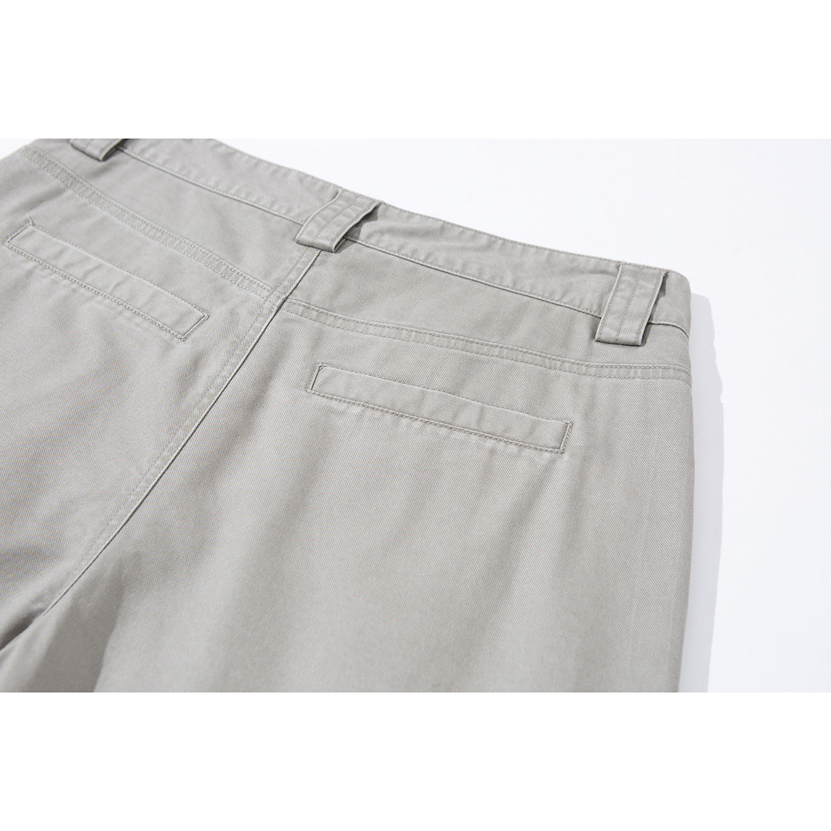 Close-up of the back of light gray trousers showing the waistband, belt loops and two welt pockets.