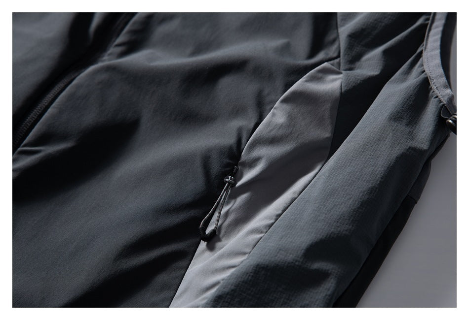 Close-up of a charcoal jacket side panel with a small hanging drawcord toggle.