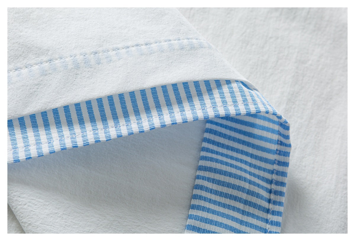 Close-up of white fabric with blue-and-white striped trim and visible stitching.