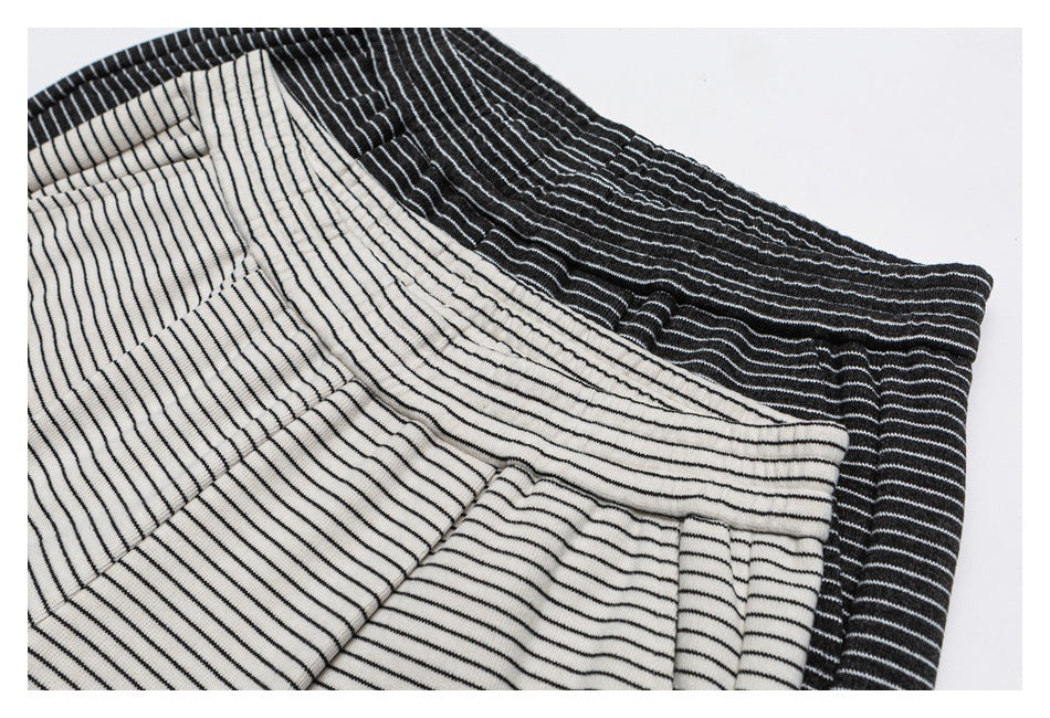 Close-up of cream and black striped pants layered together, showing their elastic waistbands and pocket seams.