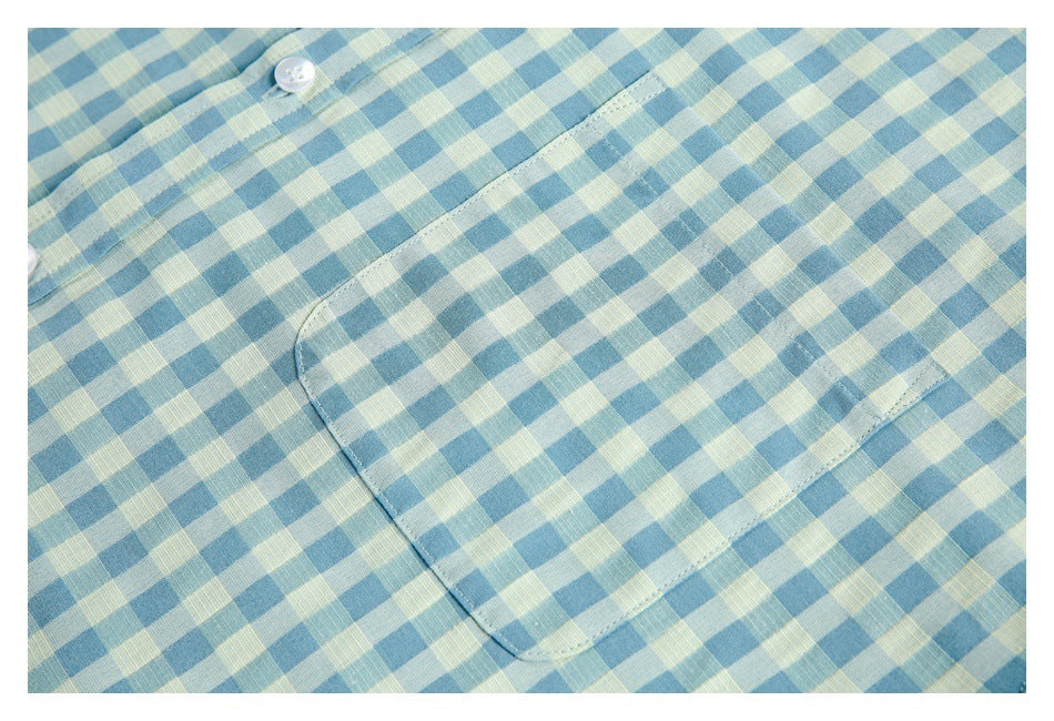 Close-up of a blue and pale yellow gingham shirt with a button and stitched chest pocket.
