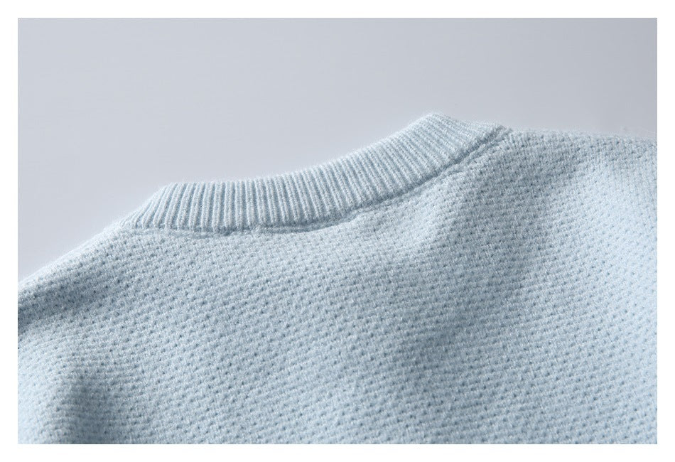 Close-up of the ribbed neckline and knit shoulder of a pale blue sweater.