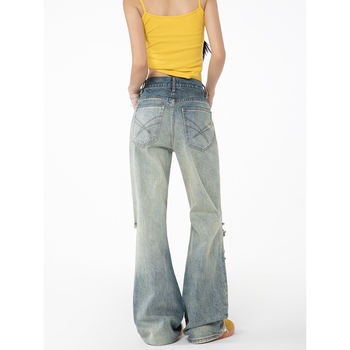 Back view of a model wearing a yellow camisole and light-wash wide-leg jeans with rear patch pockets.