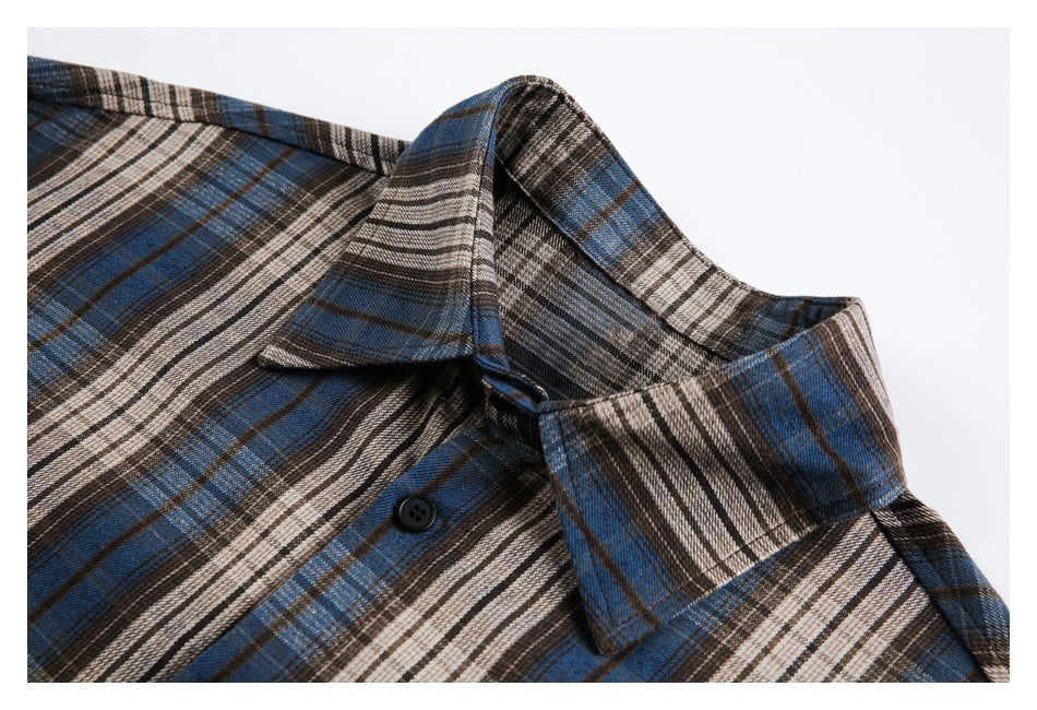 Close-up of the plaid shirt's pointed collar, shoulder seam and a black button.