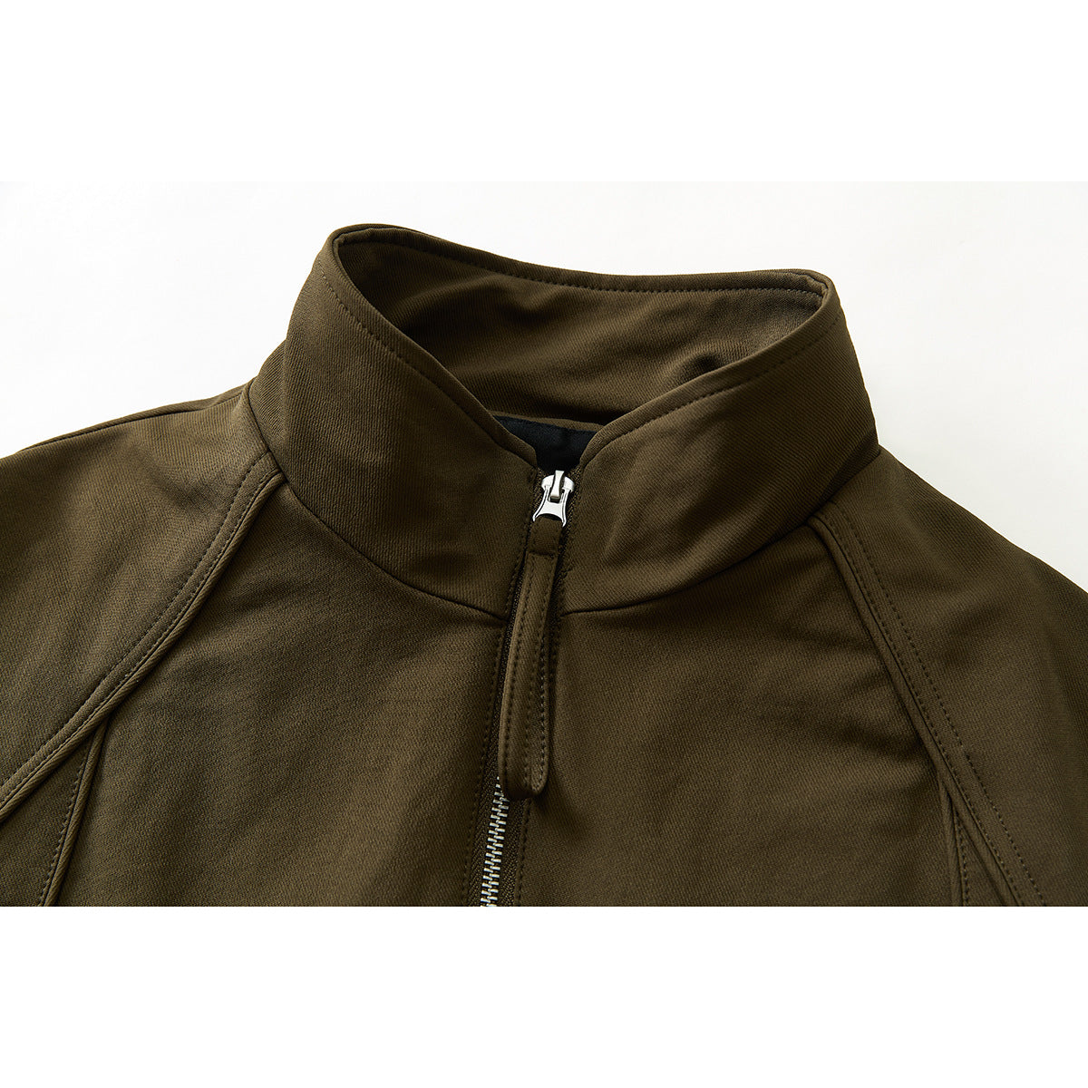 Close-up of an olive-brown jacket's raised collar, front zipper, and curved shoulder seams.