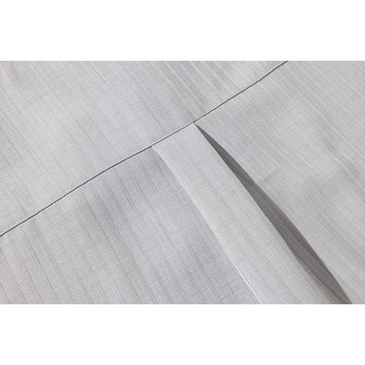 Close-up of a stitched seam and pleat in the subtle striped fabric of a light gray shirt.