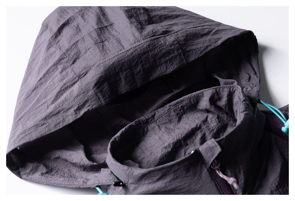 Close-up of a dark gray-purple jacket hood and collar with turquoise drawcord hardware.