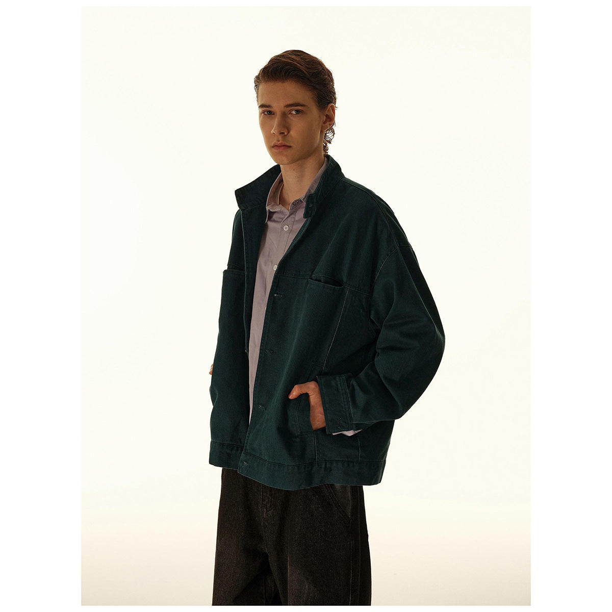 Model in a dark teal oversized jacket with large pockets, shown from a three-quarter angle.