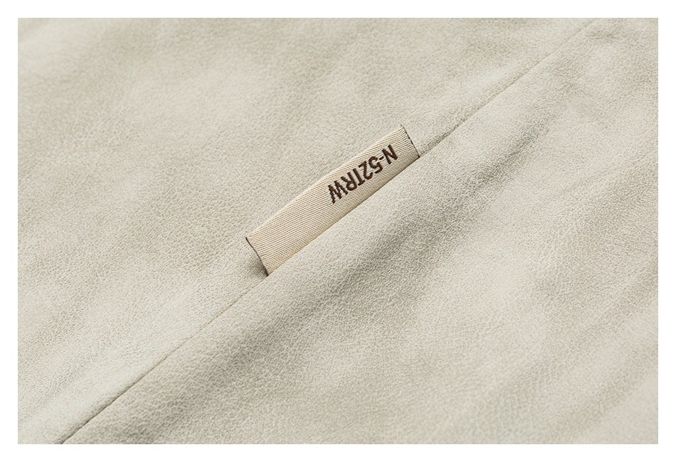 Close-up of light beige fabric with a small sewn-in label bearing dark lettering.