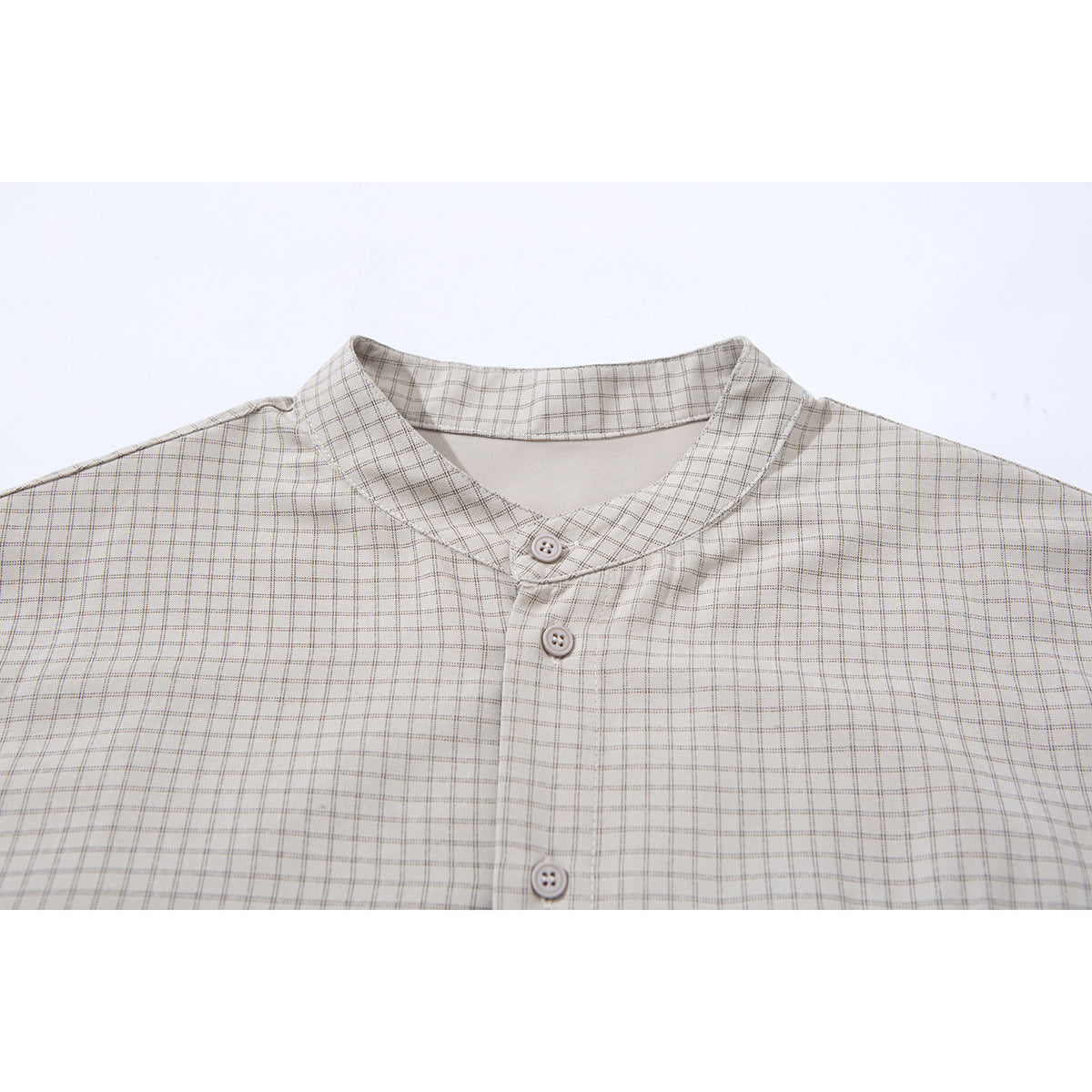 Close-up of a light beige checked shirt showing its stand collar and front buttons.