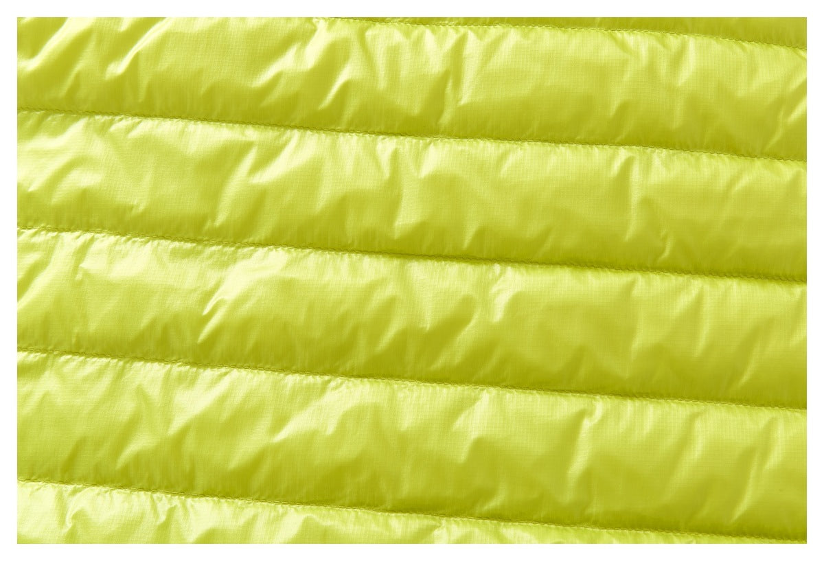 Close-up of bright chartreuse fabric with horizontal stitched channels and a lightly crinkled surface.