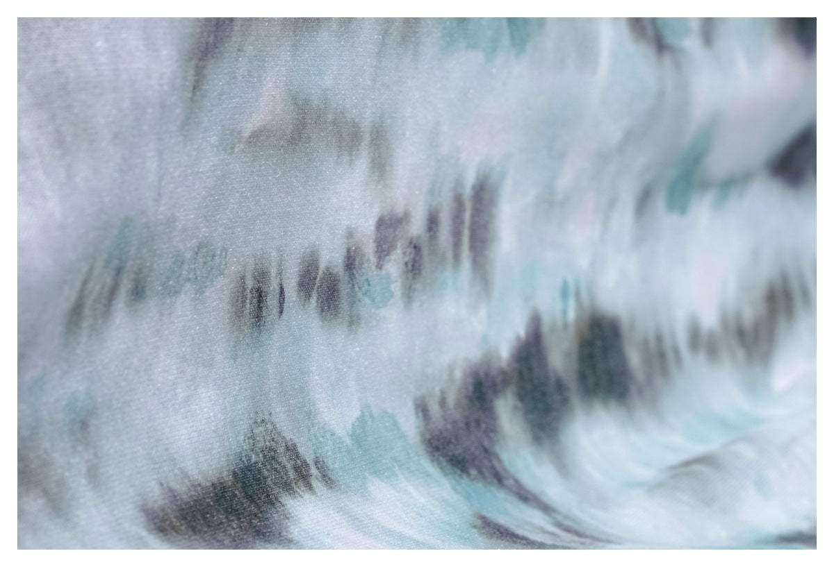 Macro view of pale aqua and gray tie-dye fabric with a soft, mottled print.