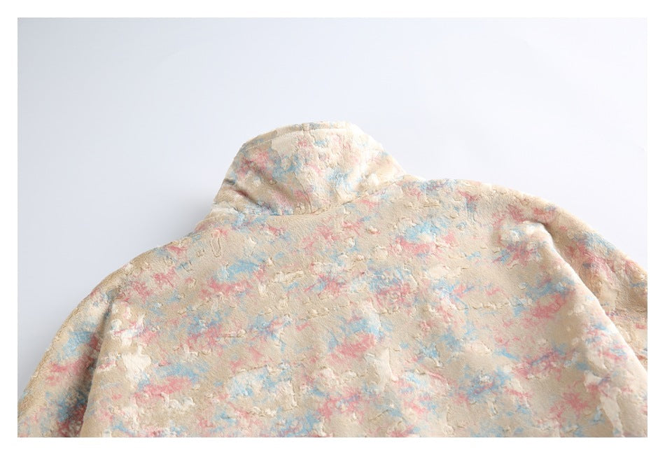 Close view of a cream plush jacket with a hood and a mottled pink and blue pattern.