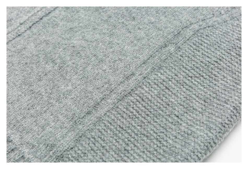 Close-up of light gray knit fabric showing a diagonal seam and varied stitch textures.
