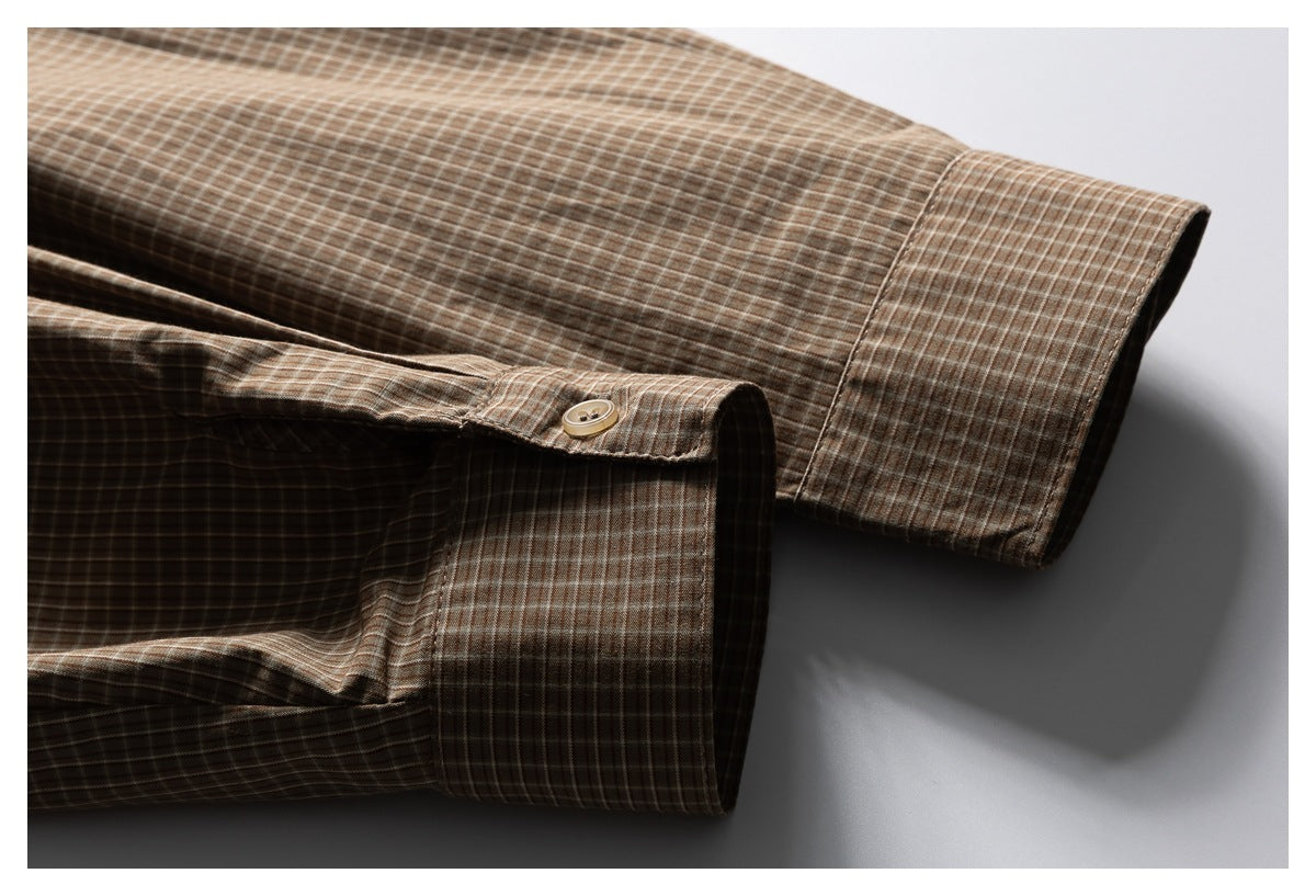 Close-up of the brown checked shirt's buttoned sleeve cuff and seam.