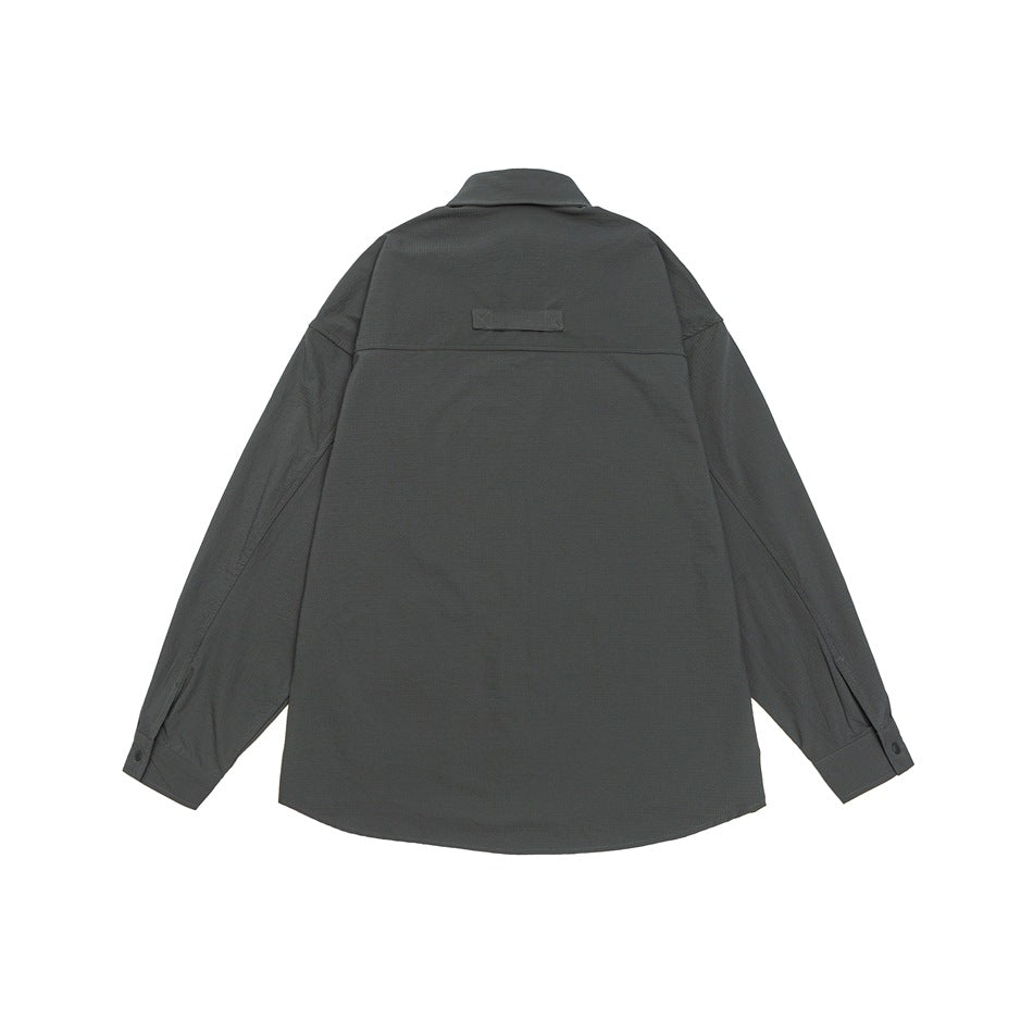 Back view of a charcoal-gray long-sleeved shirt laid flat, with a collar, button cuffs, and a small plain patch.