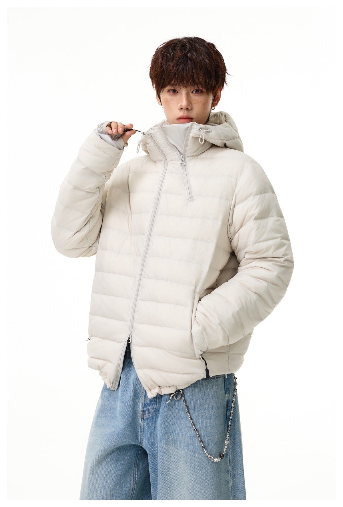 Model wearing off-white quilted hooded jacket with angled zipper and hand in pocket, with light-wash jeans