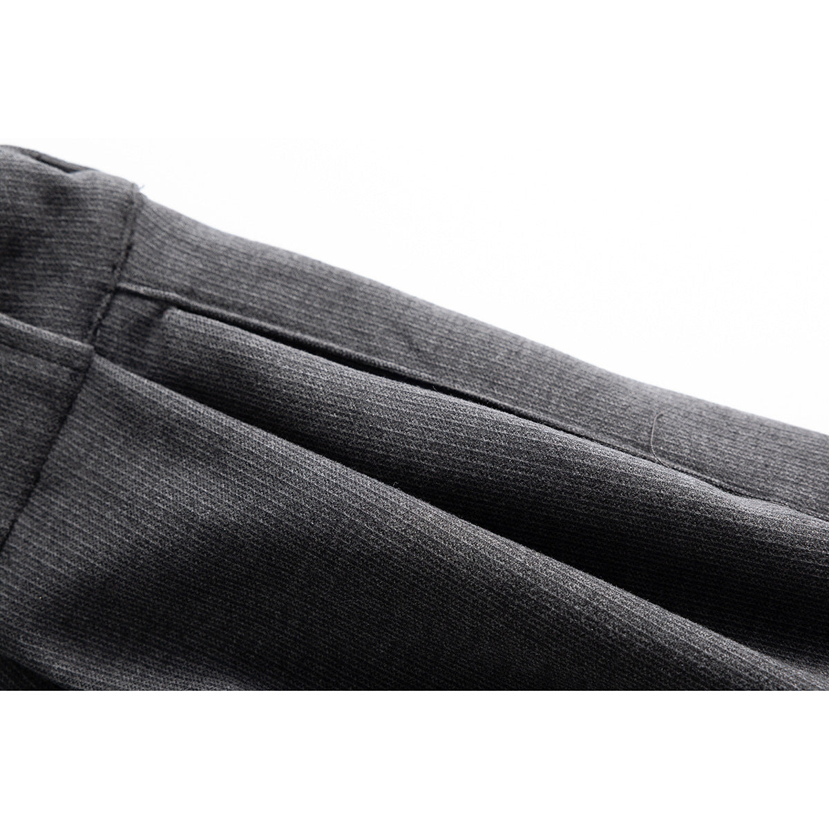 Close-up of charcoal gray trouser fabric and a slanted pocket opening.
