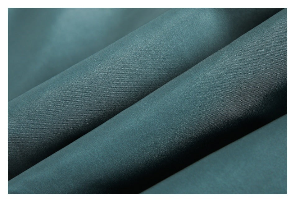 Macro close-up of teal fabric folded into soft diagonal ridges.