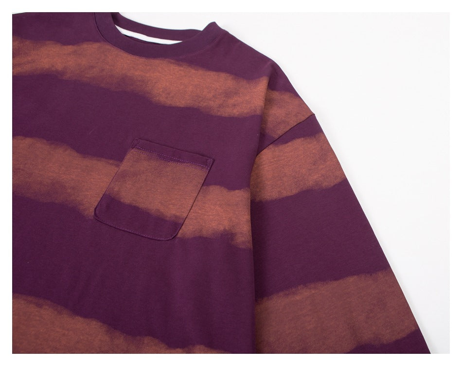 Close-up of a plum crewneck sweatshirt front with rust-brown wavy stripes and a matching chest pocket.