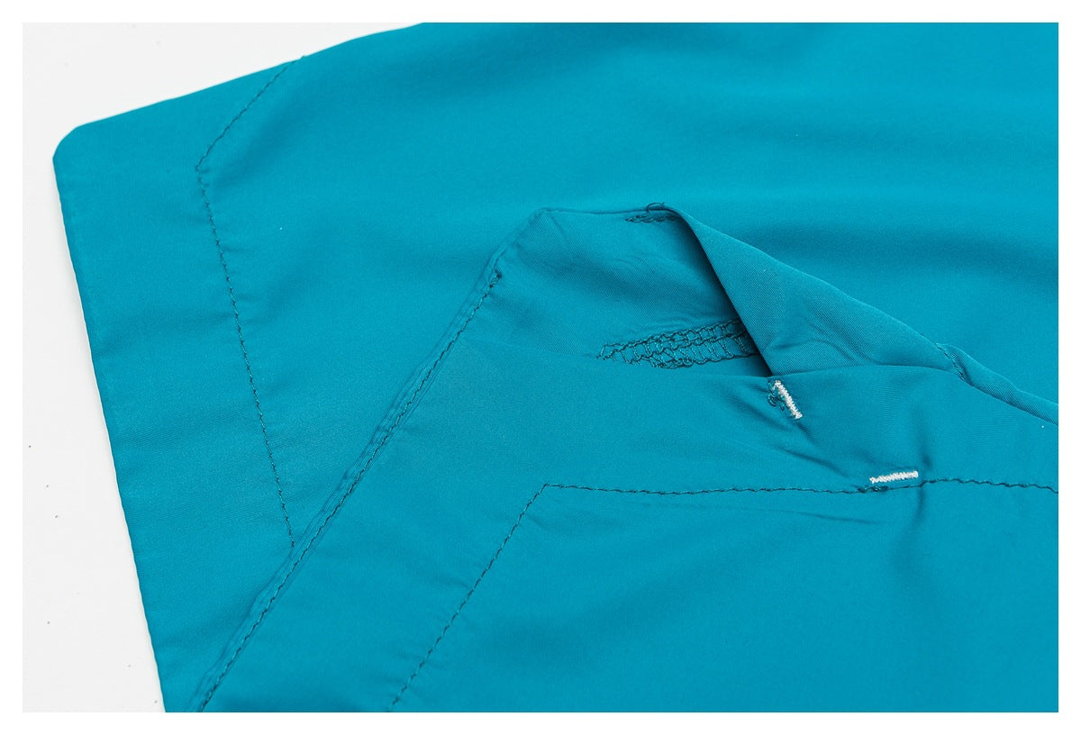 Close-up of turquoise garment fabric showing seam stitching and a small white buttonhole.
