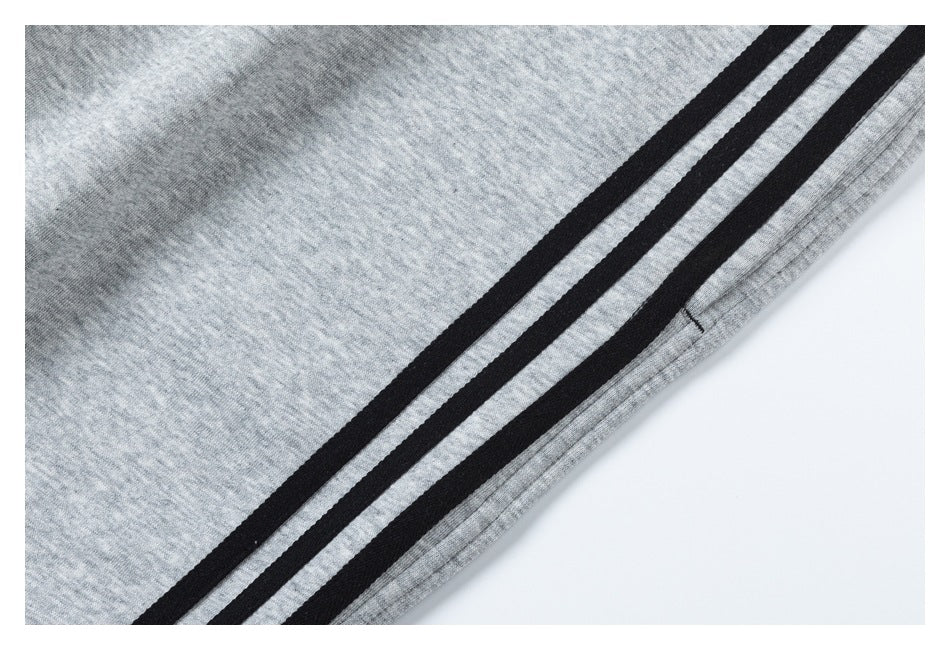 Close-up of light gray pants with three black stripes running along the side near the hem.