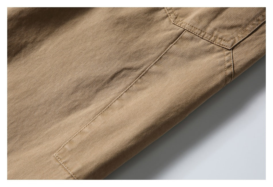Close-up of tan-brown garment fabric showing stitched seams and a pocket edge.