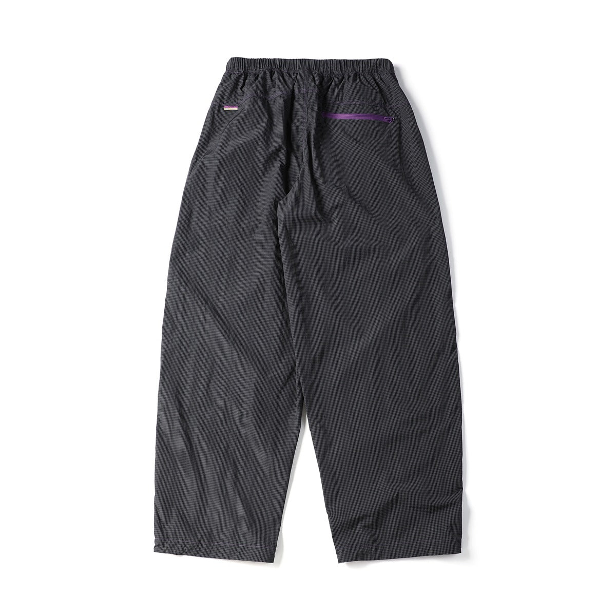 Back view of loose charcoal grid-pattern trousers with an elastic waistband and a purple horizontal zip pocket.