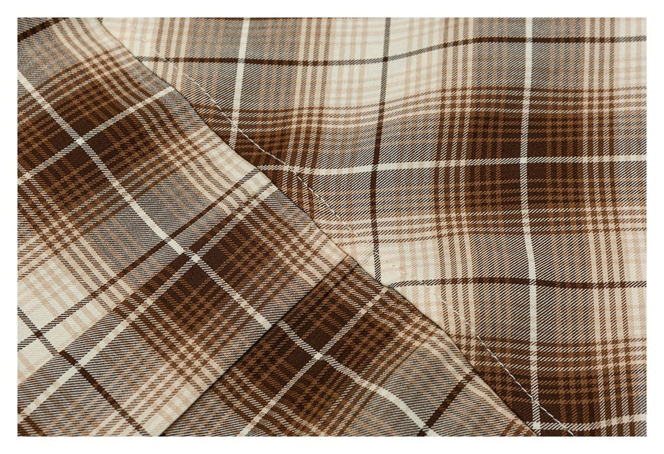 Close-up of brown and cream plaid shirt fabric with overlapping panels and visible stitching.