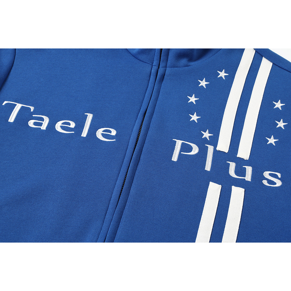 Close-up of a blue zip-up jacket with white “Taele Plus” lettering, stars, and vertical stripes.