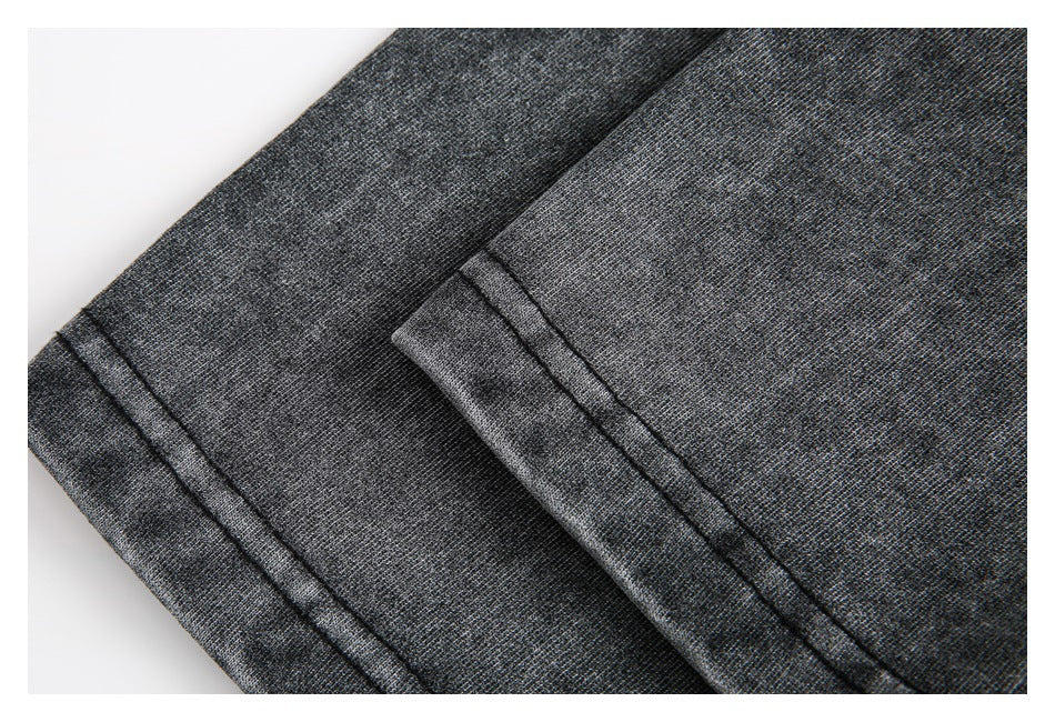 Close-up of charcoal heathered garment fabric with a folded edge and parallel dark stitching.
