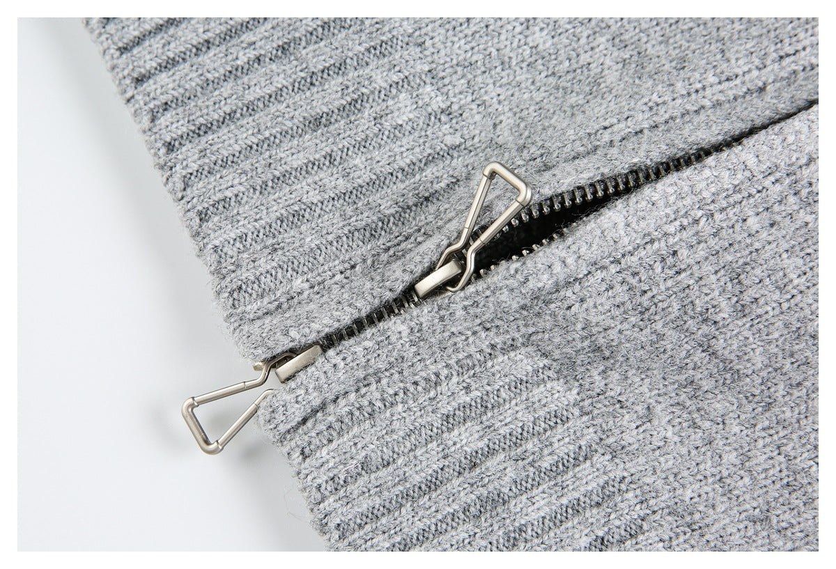 Close-up of a metal zipper and ribbed knit edging on a light gray garment.