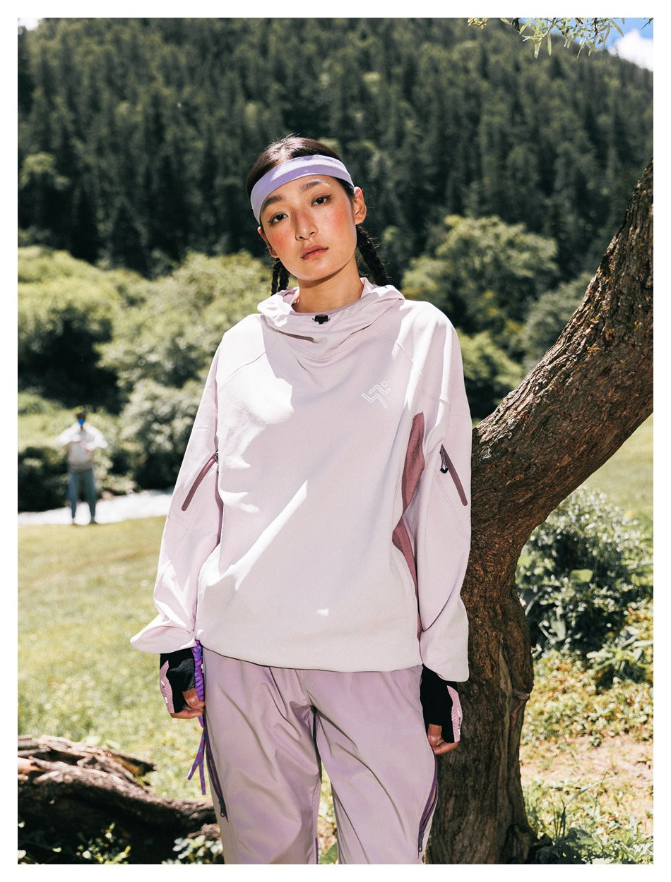 Model outdoors wearing a pale pink hooded top with sleeve zips and matching loose pants.