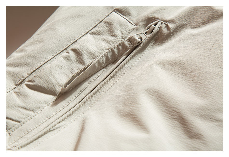Close-up of a diagonal zip pocket on cream-colored garment fabric.