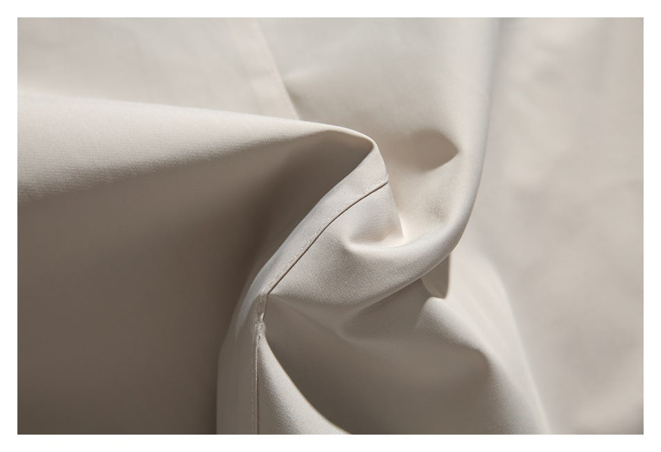 Close-up of smooth beige jacket fabric draped to show a curved stitched seam.