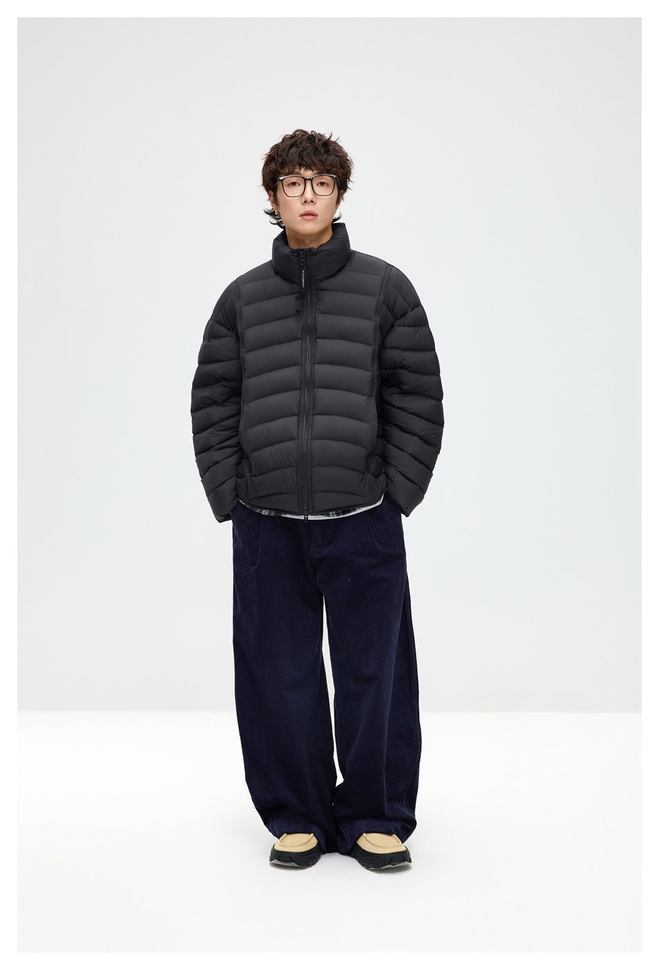Full-length model wearing a black quilted puffer jacket zipped to its high collar with navy wide-leg trousers.