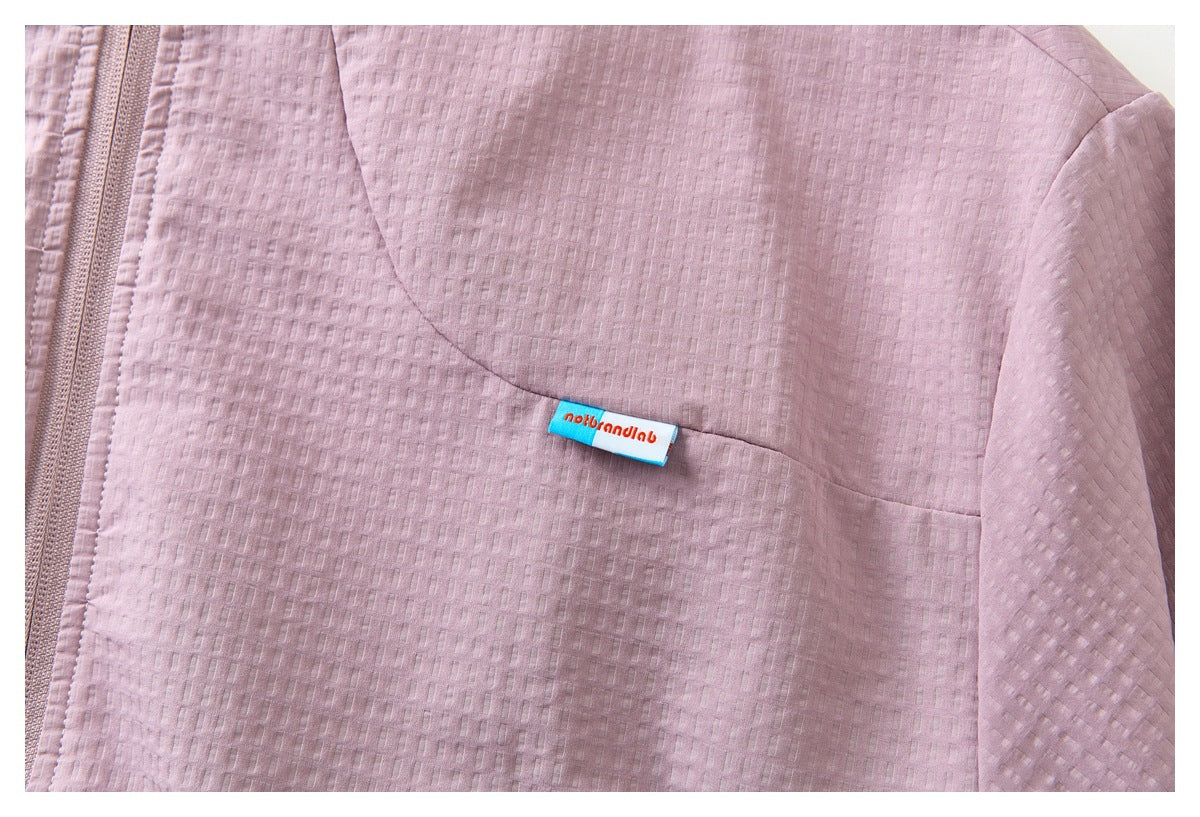 Close-up of the mauve jacket's textured chest panel, zipper edge, and small blue-and-white fabric label.