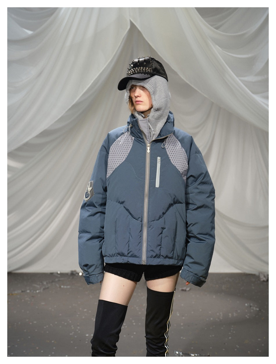 Closer front view of a model wearing a blue-gray puffer jacket with dotted shoulder panels and zip pockets.
