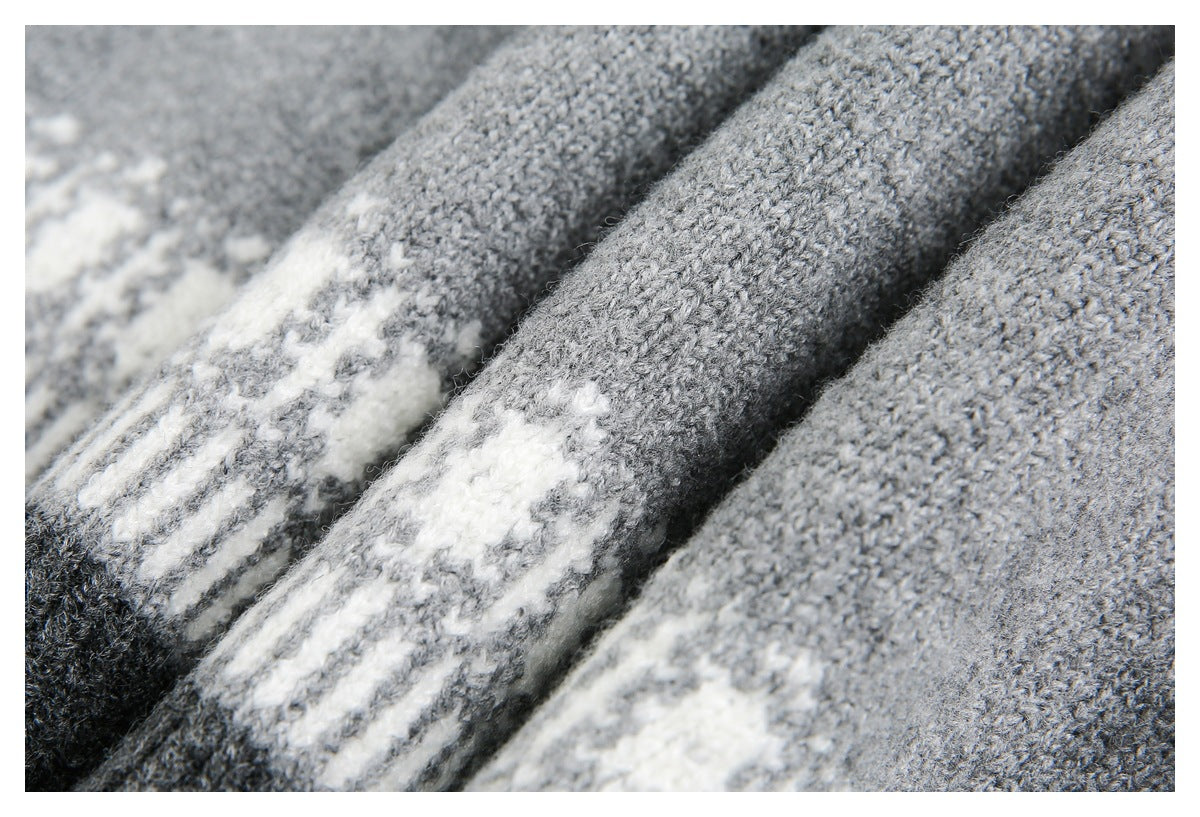 Macro view of gray knit sweater fabric with a white geometric pattern and visible yarn texture.