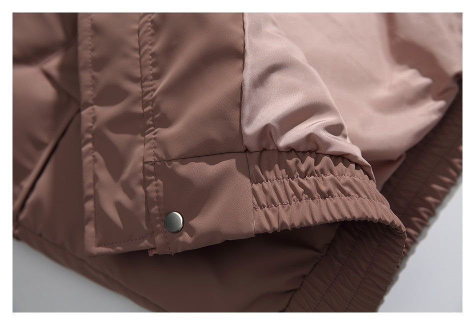 Close-up of a dusty mauve jacket sleeve with an elasticated cuff and a snap-fastener tab.