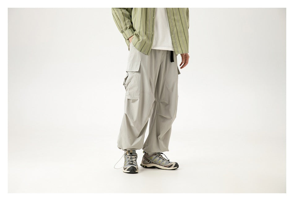 Cropped model wearing loose light gray cargo pants with multiple flap pockets, shown from a front three-quarter angle.