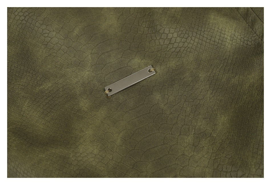 Close-up of a small blank metal plate on the olive jacket’s textured surface.