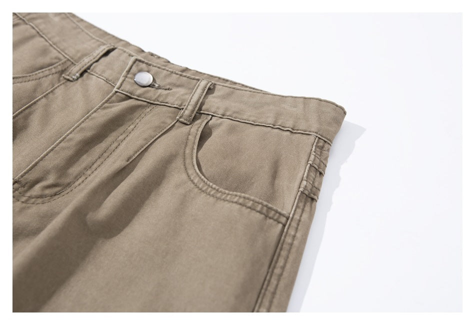 Close-up of taupe pants showing the front waistband, button, belt loop, and curved pocket.