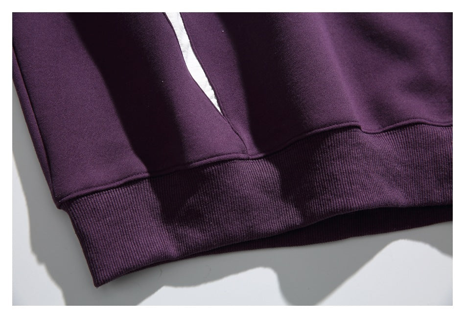 Close-up of a dark purple sweatshirt hem with a wide ribbed waistband.