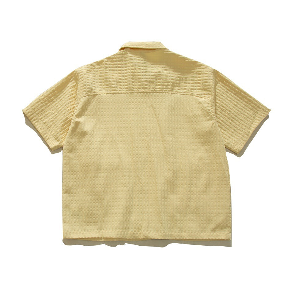 Back view of a pale yellow short-sleeve collared shirt with a textured pattern.