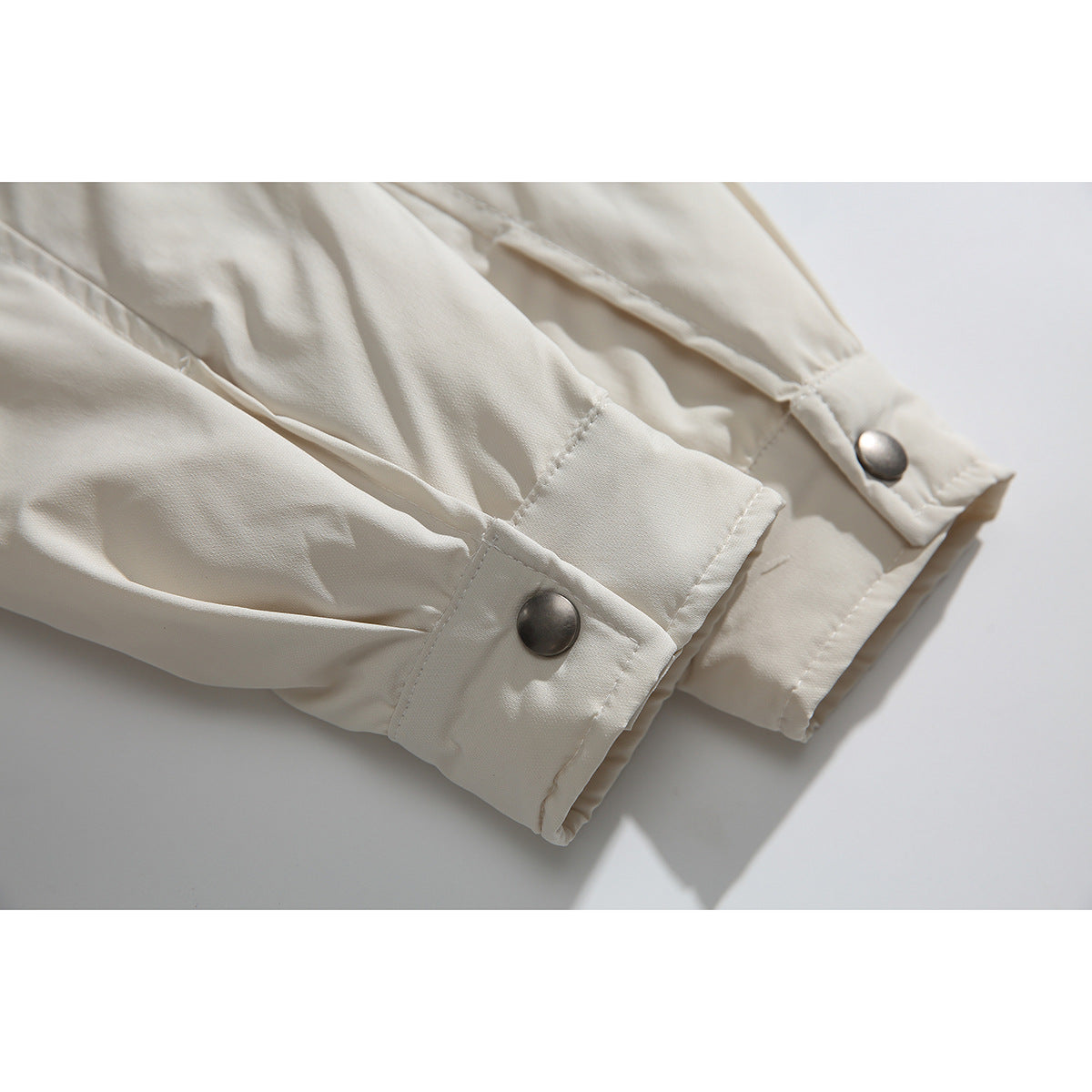 Close-up of ivory shirt jacket sleeves and cuffs, each finished with a metal snap button.