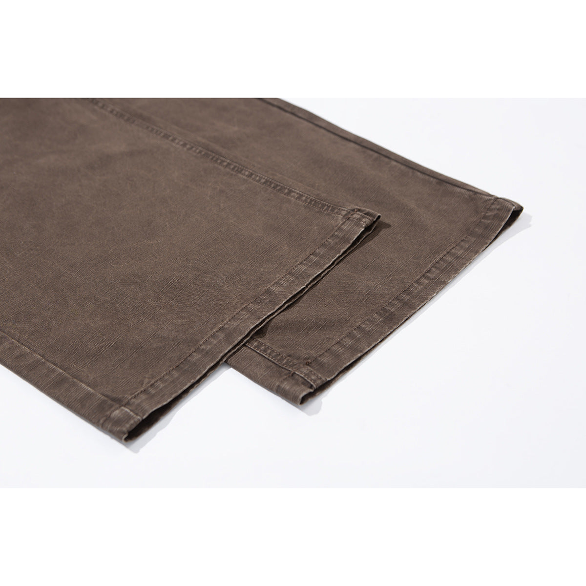 Close-up of the brown trousers' leg hems and stitched seams.