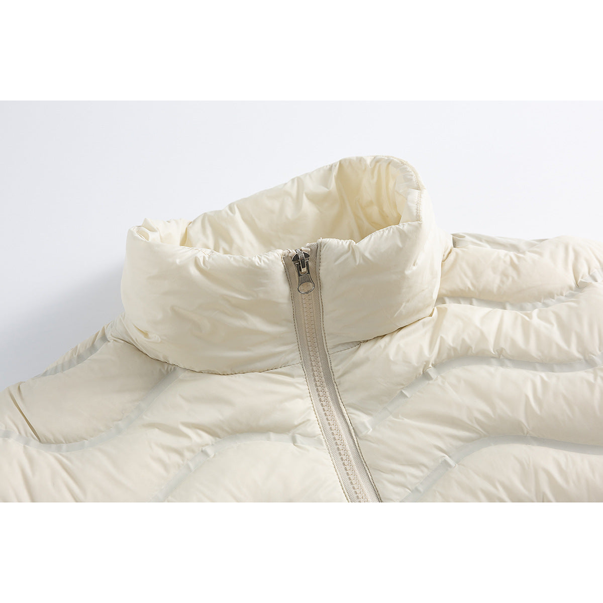 Close-up of an ivory quilted jacket's tall collar and front zipper.